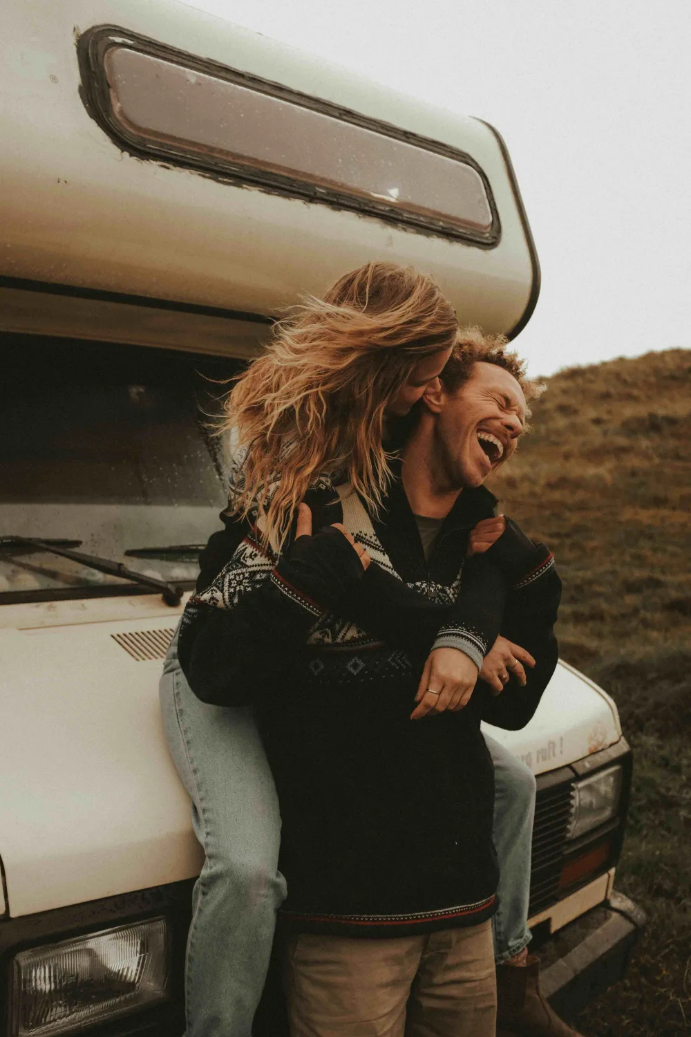 Casal abraçado e sorrindo durante uma viagem